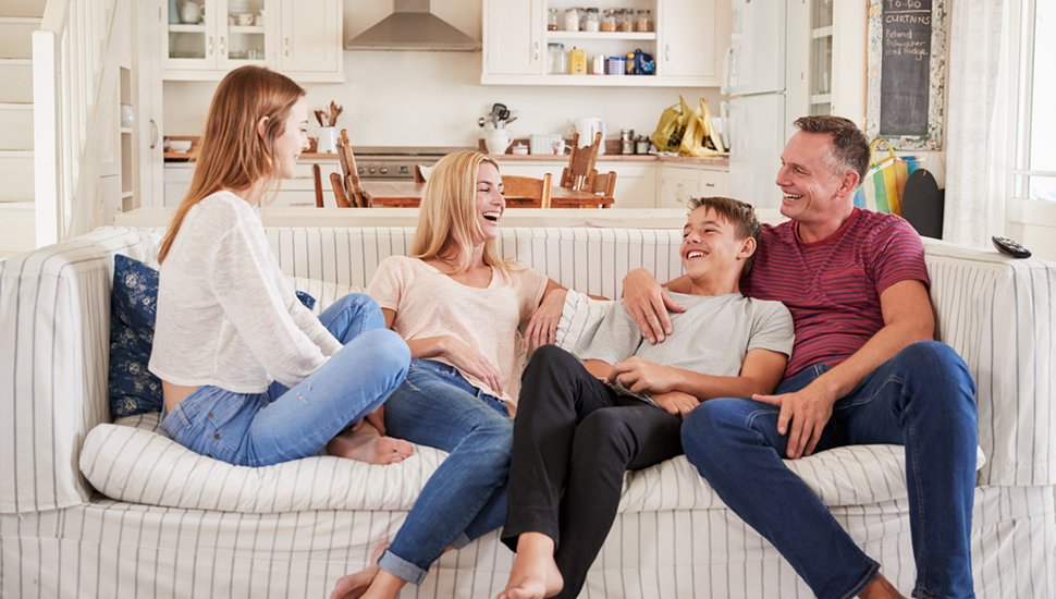 A family sits on the couch laughing while having a discussion.