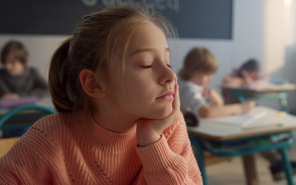 A young female student relaxes in class with her eyes closed.