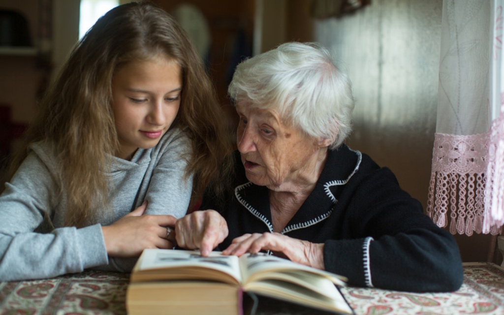 Teen girl and grandmother read a book together.