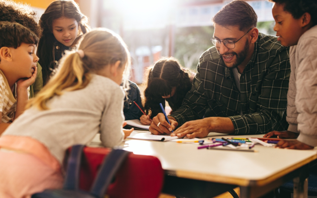 Male teacher works with elementary students.