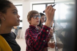 College,Student,Writing,On,White,Board,,Solving,Problem,With,Classmates