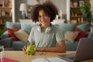 Teenage boy putting coins into a piggy bank.