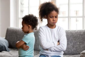 Two siblings, a young boy and girl, are facing away from each other angry.