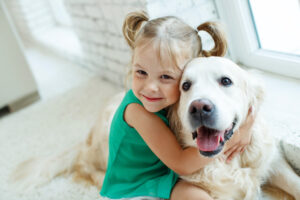 A young girl smiling and hugging her pet dog