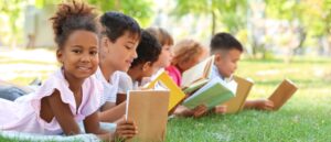 Children laying in the grass reading a book
