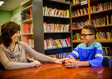 Guidance counselor and teenage boy in school library smiling