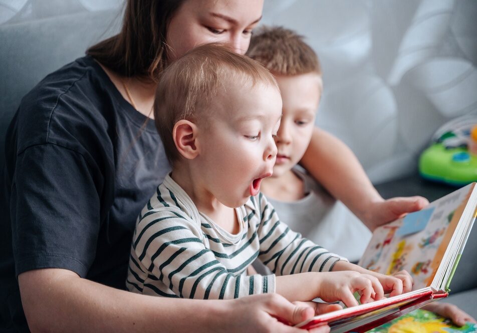 Mother,And,Children,Reacting,Emotionally,While,Reading,Colorful,Book,Together,
